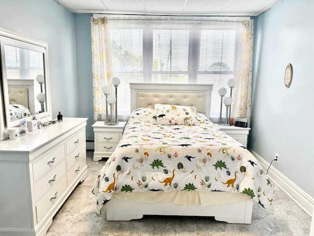 bedroom featuring baseboard heating, multiple windows, and a drop ceiling