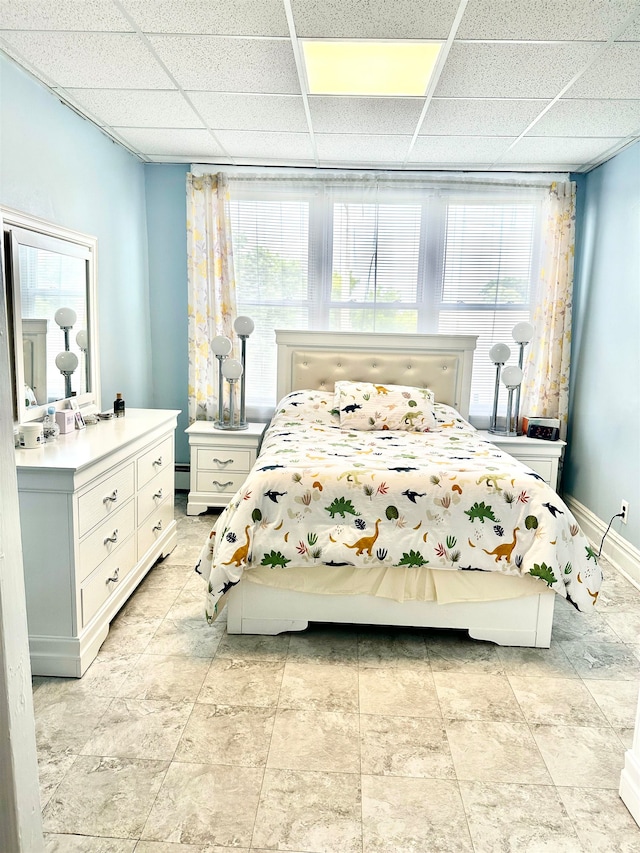 bedroom featuring baseboard heating, a paneled ceiling, and multiple windows