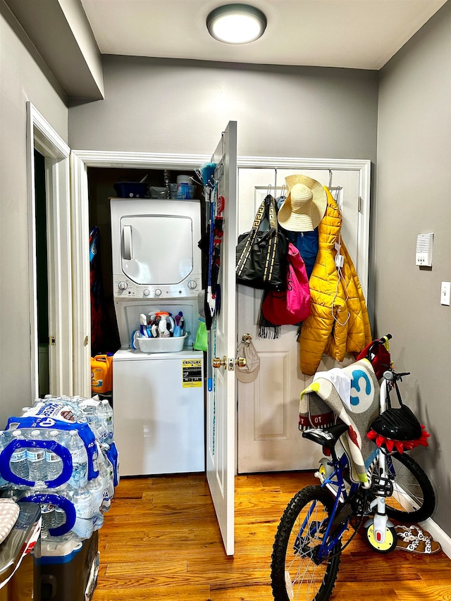 laundry room with hardwood / wood-style floors and stacked washer / dryer