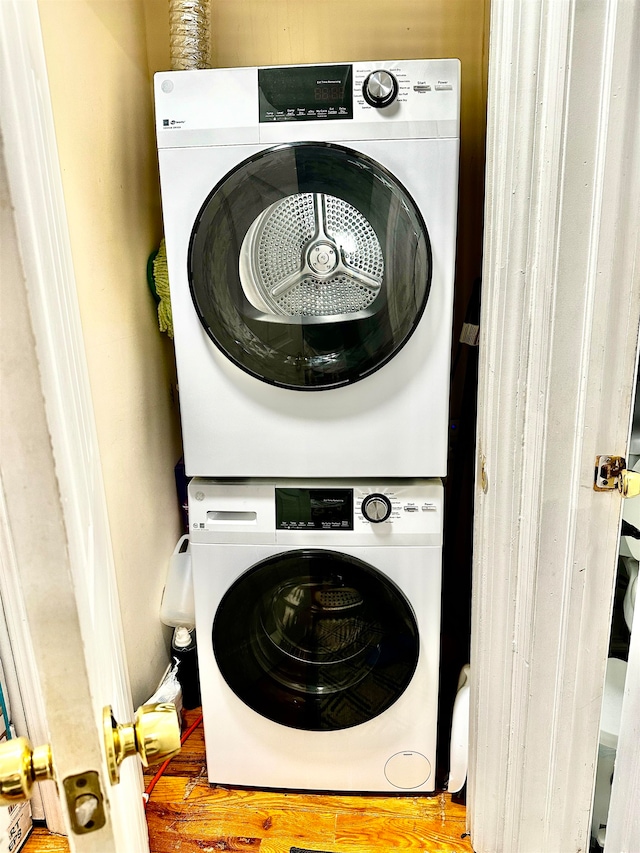 laundry room featuring hardwood / wood-style flooring and stacked washer / drying machine