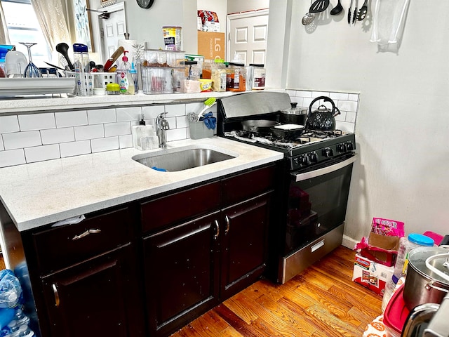 kitchen featuring backsplash, sink, light hardwood / wood-style flooring, and gas stove