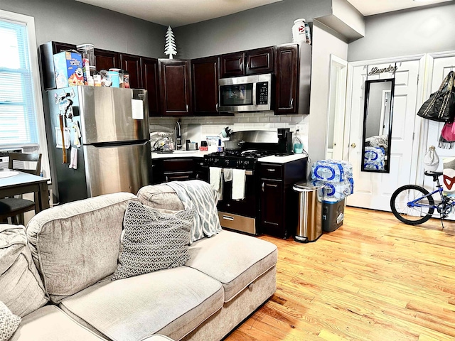 kitchen featuring dark brown cabinetry, decorative backsplash, stainless steel appliances, and light hardwood / wood-style flooring