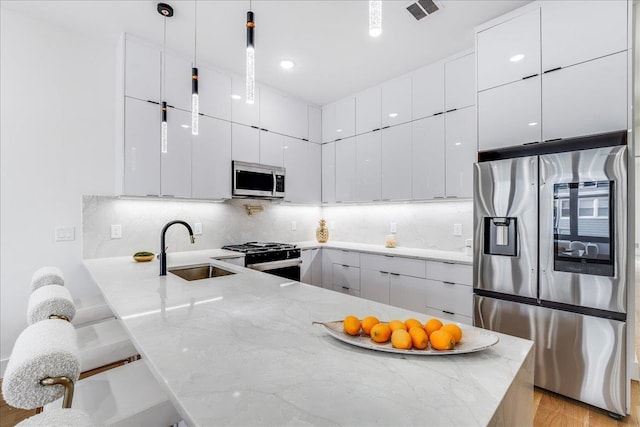 kitchen featuring kitchen peninsula, hanging light fixtures, sink, white cabinets, and stainless steel appliances