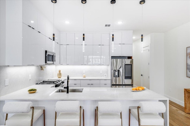 kitchen featuring sink, hanging light fixtures, stainless steel appliances, and a breakfast bar area