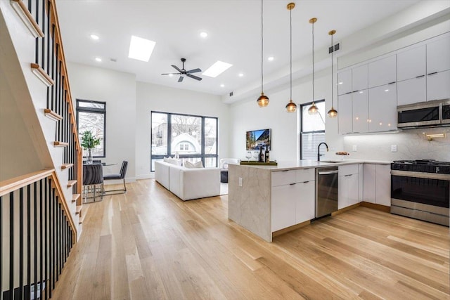 kitchen featuring backsplash, white cabinetry, hanging light fixtures, and stainless steel appliances