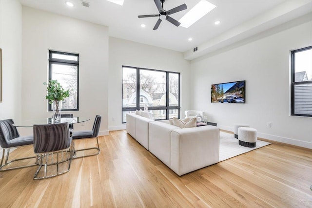 living room featuring plenty of natural light, light hardwood / wood-style flooring, and a skylight