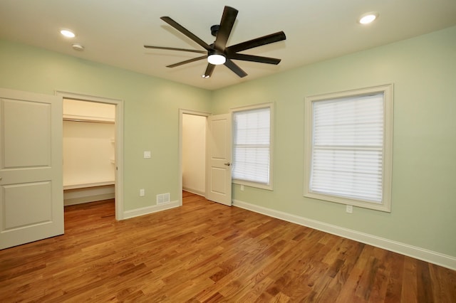 unfurnished bedroom with a closet, a spacious closet, light hardwood / wood-style flooring, and ceiling fan