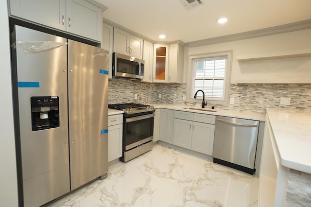 kitchen with gray cabinetry, sink, light stone countertops, tasteful backsplash, and stainless steel appliances