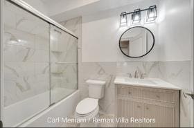 full bathroom featuring vanity, enclosed tub / shower combo, tile walls, and toilet