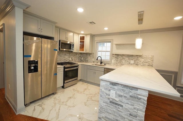 kitchen with kitchen peninsula, gray cabinetry, stainless steel appliances, sink, and pendant lighting