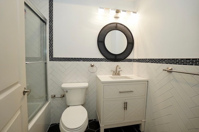 full bathroom featuring shower / bath combination with glass door, toilet, and tile walls