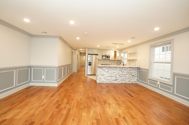 kitchen featuring kitchen peninsula, stainless steel appliances, crown molding, white cabinets, and light hardwood / wood-style floors