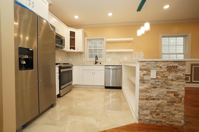 kitchen with white cabinets, decorative light fixtures, stainless steel appliances, and crown molding