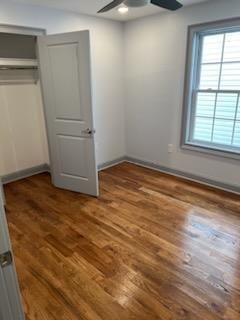 unfurnished bedroom with ceiling fan and dark wood-type flooring