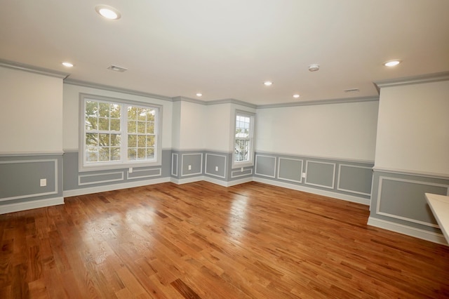 empty room with a wealth of natural light, ornamental molding, and hardwood / wood-style flooring