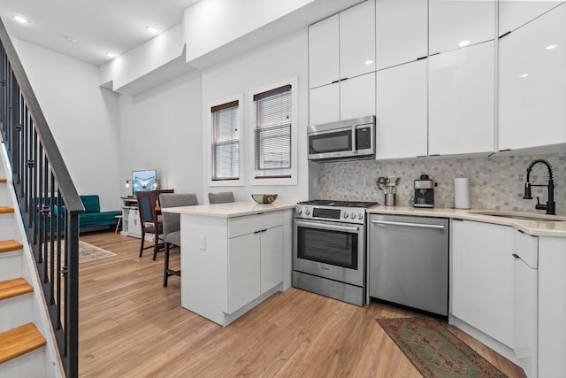 35 Manhattan Ave Unit 4, Jersey City, NJ 07307 - kitchen featuring appliances with stainless steel finishes, modern cabinets, light wood-type flooring, backsplash, and recessed lighting