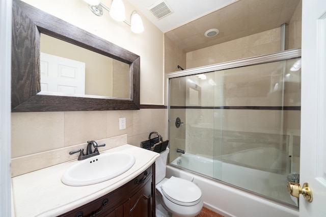 bathroom featuring visible vents, vanity, toilet, tile walls, and enclosed tub / shower combo