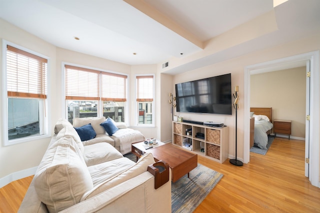 living area with visible vents, light wood-style floors, and baseboards