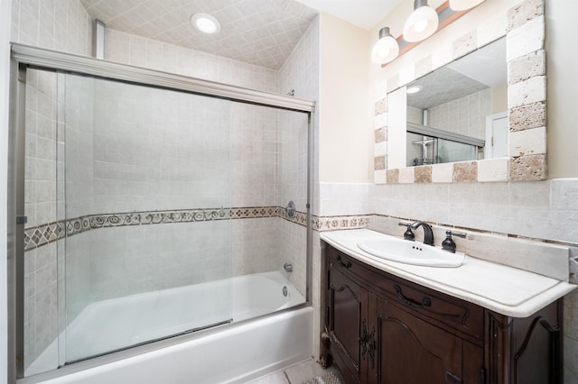 full bath with tile walls, enclosed tub / shower combo, and vanity