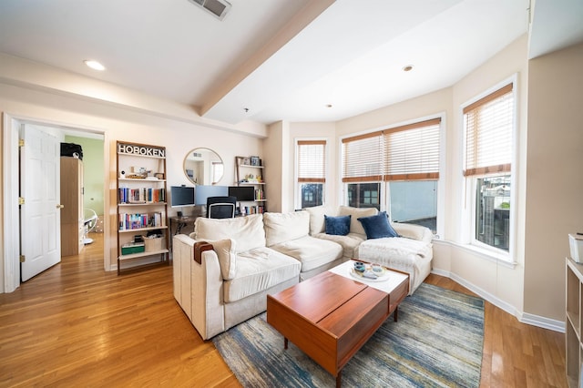 living area with visible vents, light wood-style floors, and baseboards