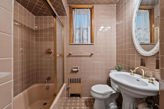 388 Kennedy Blvd, Bayonne, NJ 07002 - bathroom featuring radiator heating unit, tile walls, shower / bath combination with glass door, and tile patterned floors