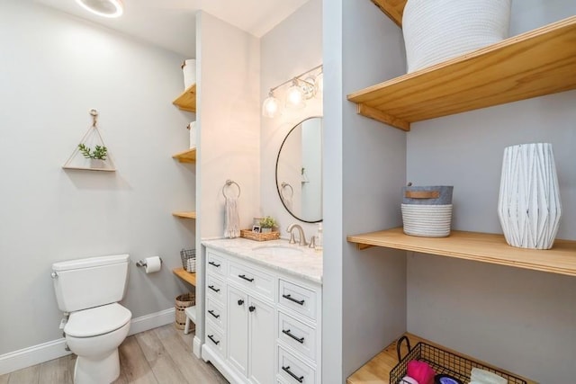 bathroom featuring vanity, toilet, wood finished floors, and baseboards