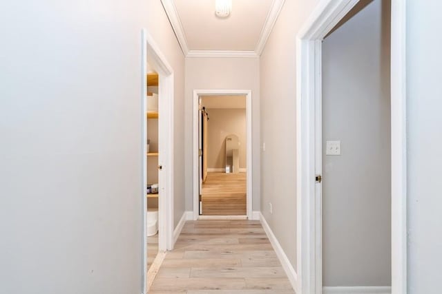 corridor with light wood-style flooring, baseboards, and ornamental molding