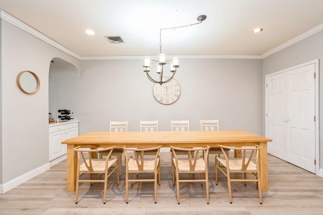 dining area with visible vents, a notable chandelier, ornamental molding, arched walkways, and light wood-style floors