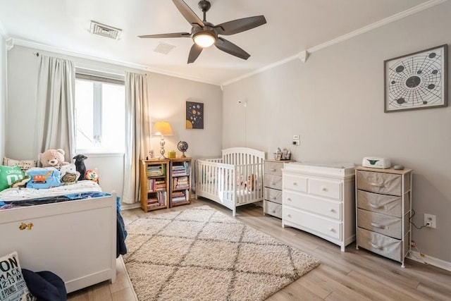 bedroom featuring visible vents, baseboards, ornamental molding, light wood-style floors, and a ceiling fan