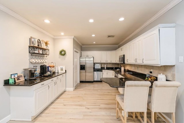 kitchen with a peninsula, light wood-style flooring, stainless steel appliances, white cabinets, and crown molding