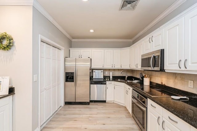 kitchen with appliances with stainless steel finishes, white cabinetry, and crown molding