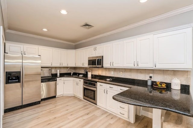 kitchen featuring visible vents, crown molding, light wood-type flooring, stainless steel appliances, and white cabinetry