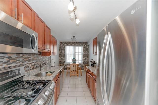 2520 Kennedy Blvd Unit 1H, Jersey City, NJ 07304 - kitchen with appliances with stainless steel finishes, a sink, brown cabinetry, light tile patterned floors, and backsplash