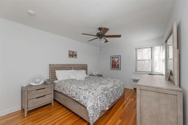 2520 Kennedy Blvd Unit 1H, Jersey City, NJ 07304 - bedroom featuring radiator, light wood-style floors, baseboards, and a ceiling fan