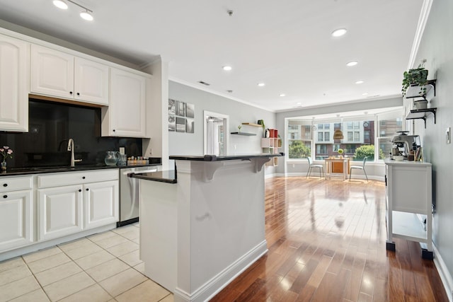 22 Ave At Port Imperial Unit 227, West New York, NJ 07093 - kitchen with stainless steel dishwasher, dark countertops, crown molding, white cabinets, and backsplash