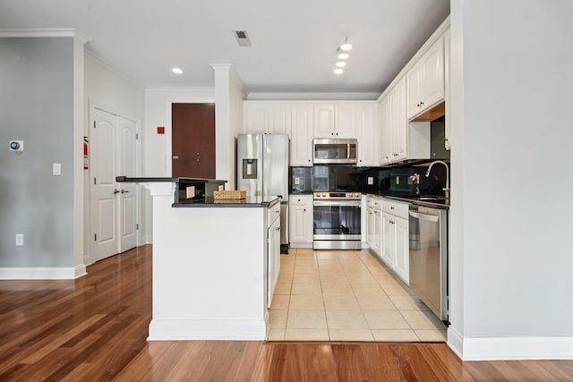 22 Ave At Port Imperial Unit 227, West New York, NJ 07093 - kitchen featuring stainless steel appliances, dark countertops, white cabinetry, light wood-style floors, and crown molding