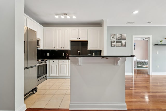 22 Ave At Port Imperial Unit 227, West New York, NJ 07093 - kitchen featuring stainless steel appliances, dark countertops, white cabinetry, crown molding, and a breakfast bar area