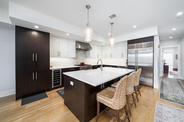 74 Madison St Unit 2, Hoboken, NJ 07030 - kitchen featuring appliances with stainless steel finishes, wine cooler, wall chimney range hood, a kitchen bar, and light countertops