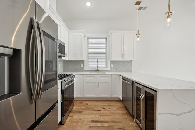 119 Van Horne St Unit 1, Jersey City, NJ 07304 - kitchen featuring appliances with stainless steel finishes, beverage cooler, light wood-type flooring, tasteful backsplash, and white cabinets