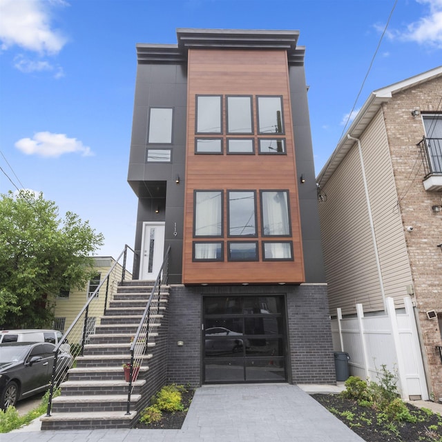 119 Van Horne St Unit 1, Jersey City, NJ 07304 - modern home with an attached garage, brick siding, driveway, and stairway