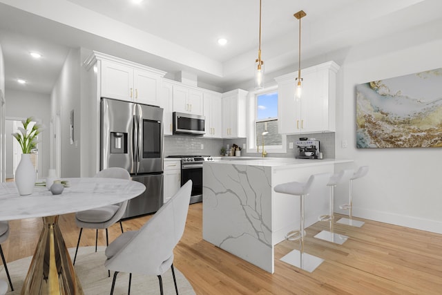119 Van Horne St Unit 1, Jersey City, NJ 07304 - kitchen with appliances with stainless steel finishes, a peninsula, tasteful backsplash, light wood-style floors, and a breakfast bar area