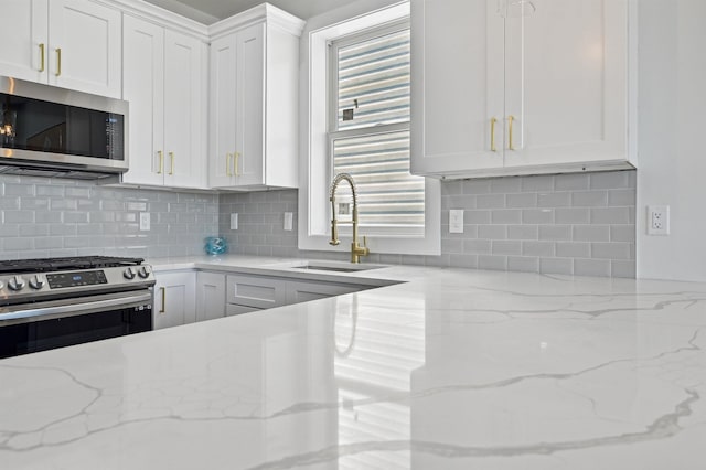 119 Van Horne St Unit 1, Jersey City, NJ 07304 - kitchen featuring appliances with stainless steel finishes, white cabinets, tasteful backsplash, and light stone counters