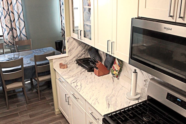 kitchen with white cabinetry, light stone countertops, dark hardwood / wood-style flooring, and range