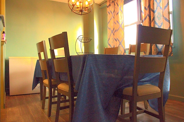 dining area featuring wood-type flooring and a notable chandelier