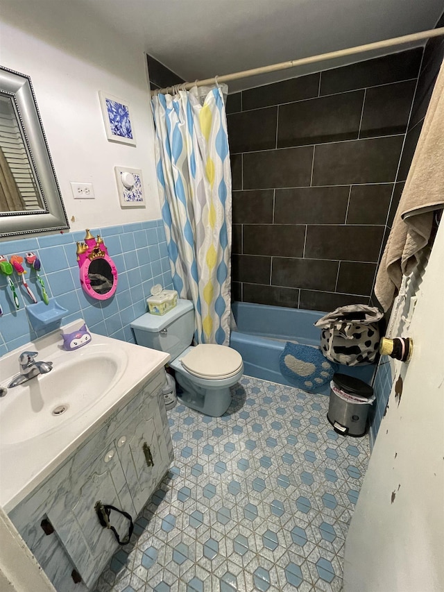 bathroom featuring shower / bath combo with shower curtain, toilet, tile walls, vanity, and wainscoting