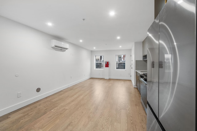 kitchen with recessed lighting, freestanding refrigerator, an AC wall unit, light wood-type flooring, and baseboards