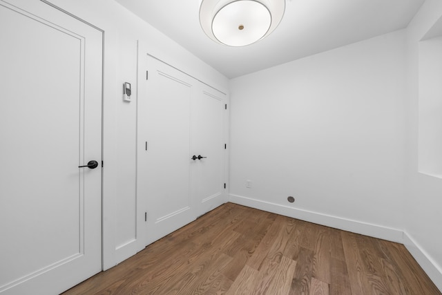 laundry room featuring baseboards and wood finished floors