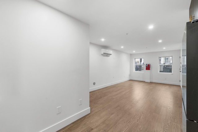 unfurnished living room with recessed lighting, baseboards, wood finished floors, and a wall mounted air conditioner