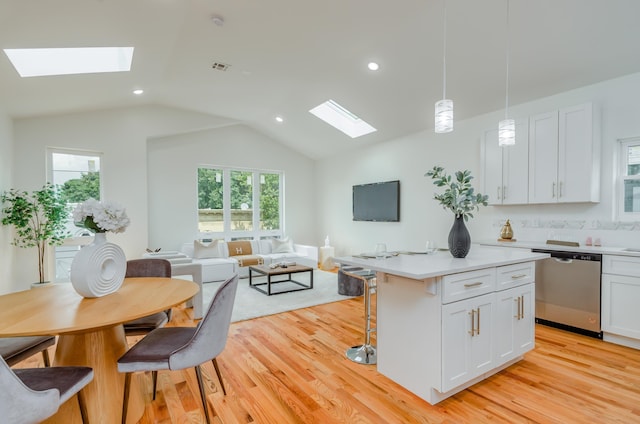 kitchen with decorative light fixtures, white cabinetry, stainless steel dishwasher, and light hardwood / wood-style flooring