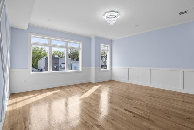 spare room with visible vents, crown molding, and a wainscoted wall